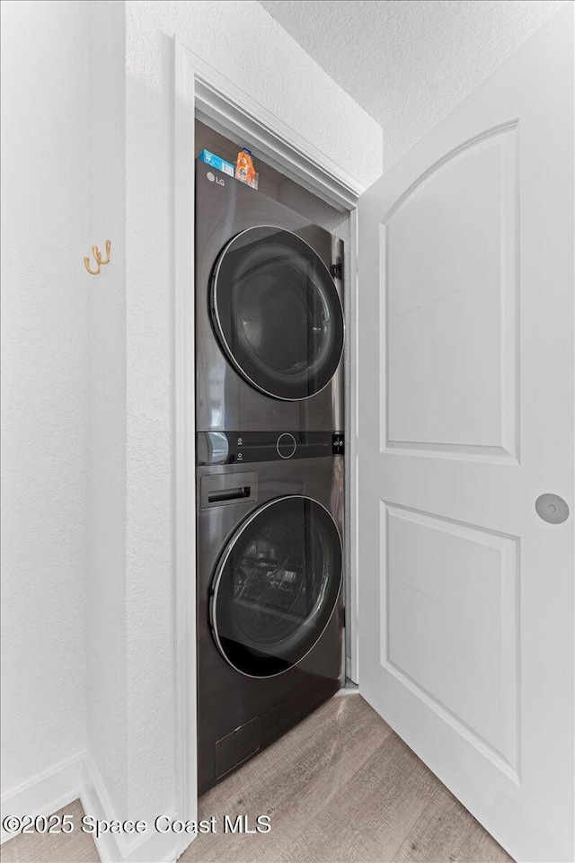 299 E Central Blvd Unit 6, Cape Canaveral, FL 32920 - laundry area featuring a textured ceiling, laundry area, stacked washer and dryer, and wood finished floors