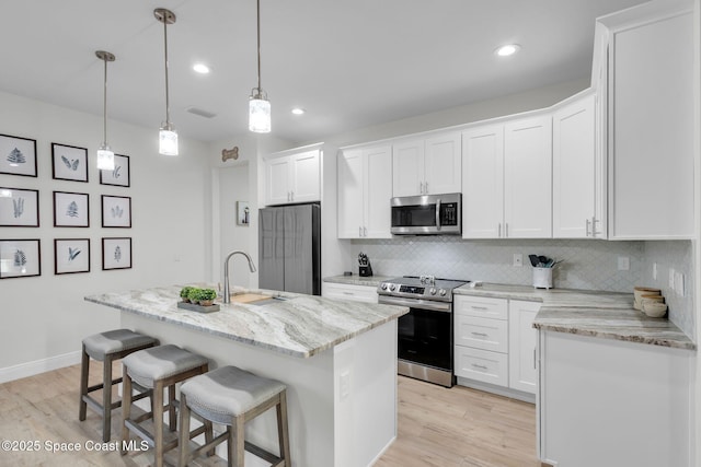 1401 Wyoming Dr SE, Palm Bay, FL 32909 - kitchen featuring a kitchen breakfast bar, white cabinetry, tasteful backsplash, a sink, and stainless steel appliances