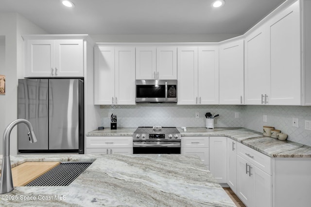 1401 Wyoming Dr SE, Palm Bay, FL 32909 - kitchen featuring tasteful backsplash, light stone countertops, a sink, white cabinets, and stainless steel appliances