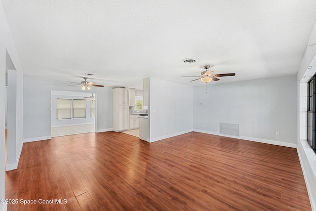unfurnished living room with visible vents, baseboards, ceiling fan, and wood finished floors