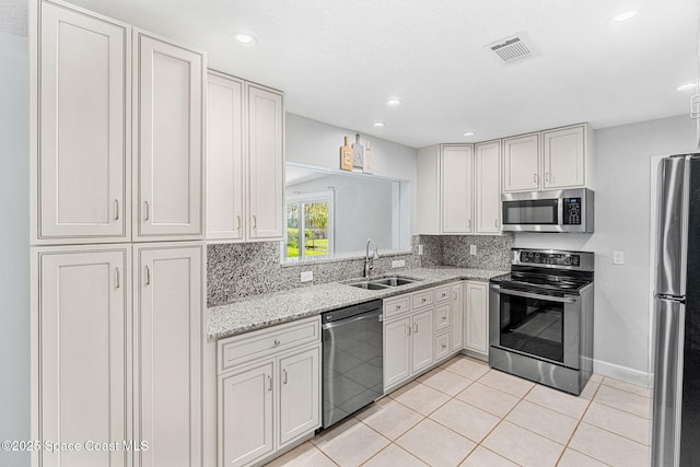 kitchen with a sink, stainless steel appliances, light tile patterned floors, backsplash, and visible vents