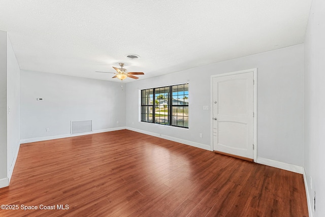 empty room featuring visible vents, a ceiling fan, and wood finished floors