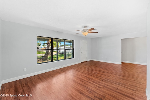empty room with baseboards, a ceiling fan, a textured ceiling, and wood finished floors
