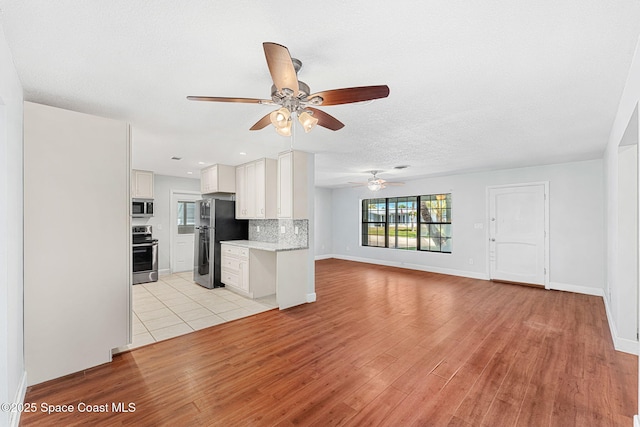 unfurnished living room featuring light wood-style floors, baseboards, ceiling fan, and recessed lighting