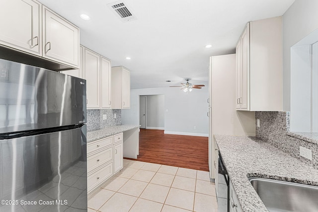kitchen with decorative backsplash, a ceiling fan, visible vents, light tile patterned floors, and stainless steel appliances