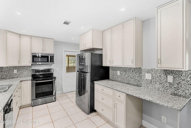 kitchen featuring visible vents, tasteful backsplash, light stone countertops, light tile patterned floors, and stainless steel appliances