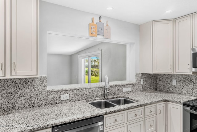 kitchen featuring light stone counters, a sink, appliances with stainless steel finishes, and backsplash