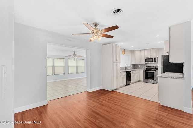 kitchen with visible vents, backsplash, a ceiling fan, appliances with stainless steel finishes, and light tile patterned floors