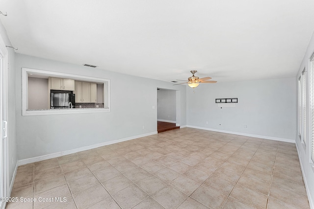 spare room featuring visible vents, baseboards, ceiling fan, and light tile patterned flooring