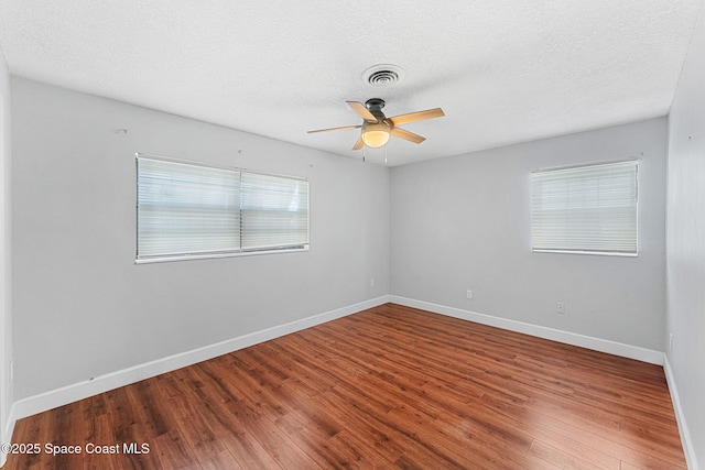 spare room with baseboards, ceiling fan, wood finished floors, and visible vents