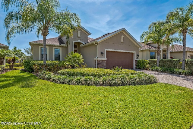 7447 Bluemink Ln, Melbourne, FL 32940 - view of front of house featuring stucco siding, an attached garage, a front lawn, driveway, and stone siding