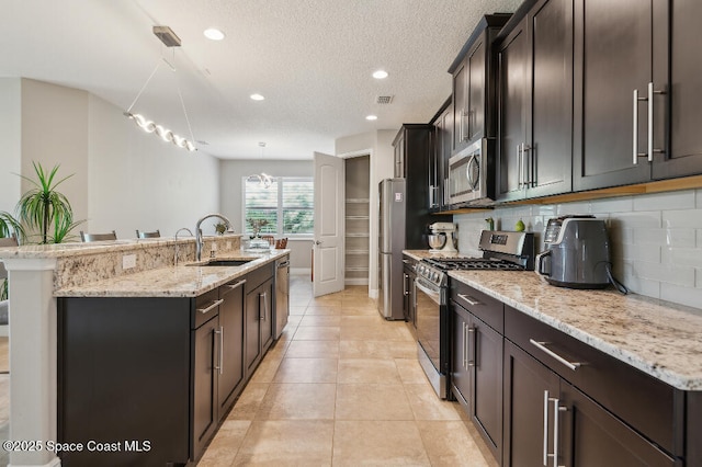 7447 Bluemink Ln, Melbourne, FL 32940 - kitchen with appliances with stainless steel finishes, a center island with sink, a sink, backsplash, and pendant lighting