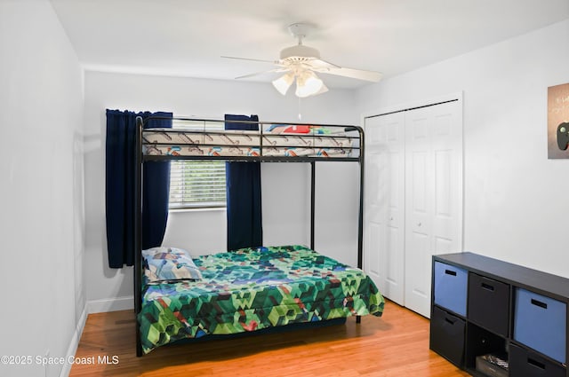 bedroom featuring a ceiling fan, baseboards, wood finished floors, and a closet