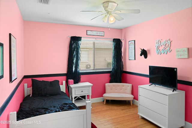bedroom with visible vents, a ceiling fan, baseboards, and wood finished floors