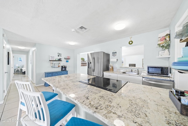 1380 Fiddler Ave, Merritt Island, FL 32952 - kitchen with visible vents, light tile patterned flooring, light stone counters, a sink, and appliances with stainless steel finishes