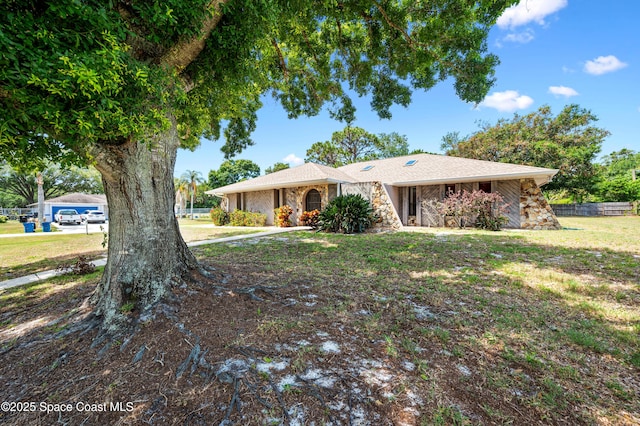 single story home featuring stone siding and a front lawn