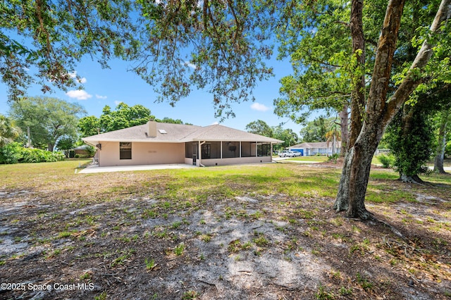 rear view of house featuring a sunroom, a patio, a yard, stucco siding, and a carport