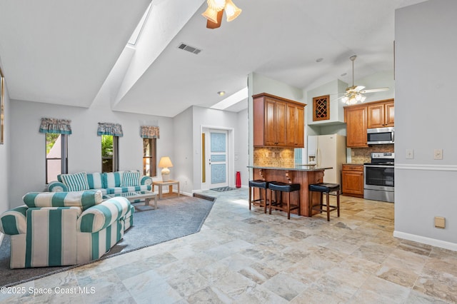 living area with a ceiling fan, lofted ceiling, baseboards, stone finish flooring, and a skylight