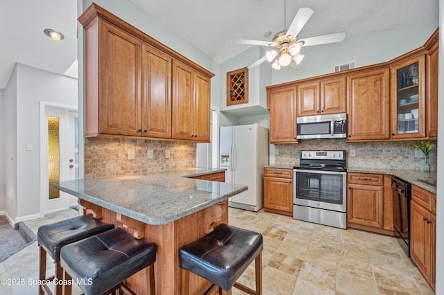 kitchen featuring stainless steel appliances, brown cabinets, a kitchen breakfast bar, and a peninsula