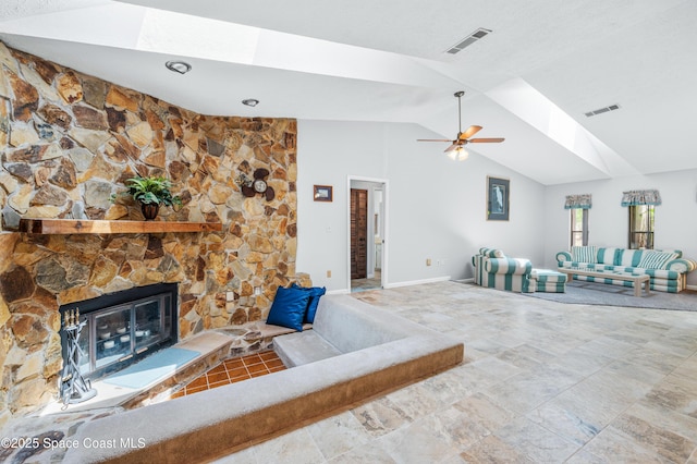 living room featuring a skylight, vaulted ceiling, ceiling fan, a fireplace, and baseboards