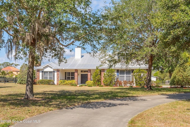 5635 N Tropical Trl, Merritt Island, FL 32953 - ranch-style home with fence, a chimney, a front yard, and brick siding