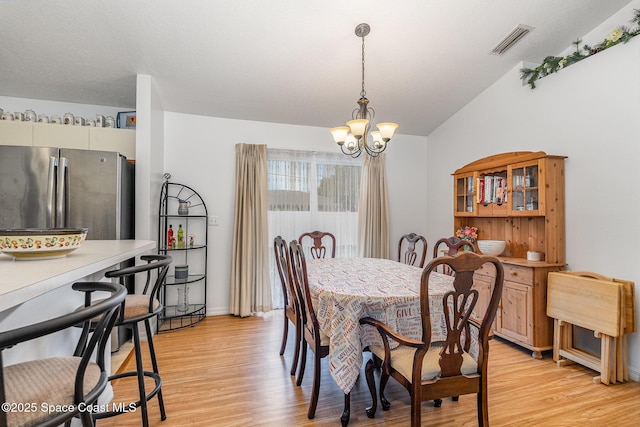 dining space featuring a chandelier, visible vents, baseboards, lofted ceiling, and light wood-style floors