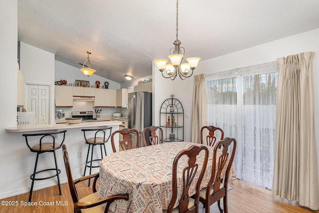 dining area with light wood finished floors, lofted ceiling, and a chandelier