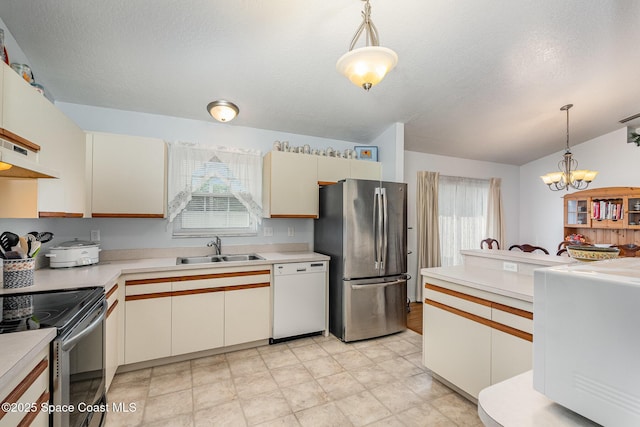 kitchen with pendant lighting, appliances with stainless steel finishes, a sink, light countertops, and a chandelier