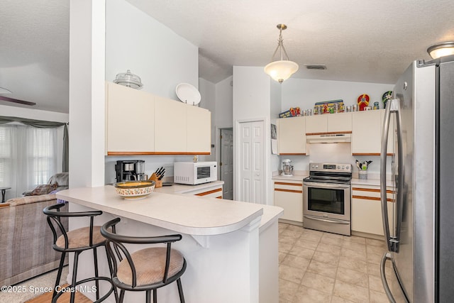 kitchen featuring visible vents, a peninsula, under cabinet range hood, vaulted ceiling, and stainless steel appliances