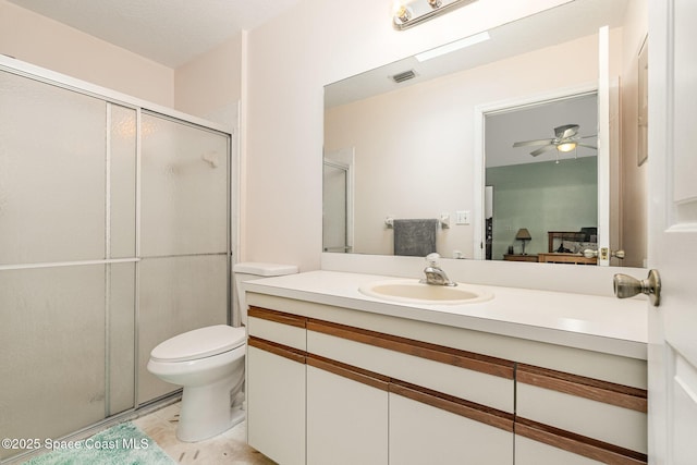 bathroom featuring ceiling fan, vanity, toilet, visible vents, and a stall shower