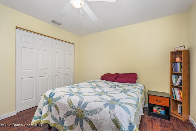 bedroom with a ceiling fan, baseboards, wood finished floors, visible vents, and a closet