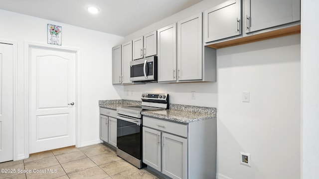 6878 Hartford Rd, Cocoa, FL 32927 - kitchen featuring stainless steel appliances, gray cabinetry, light stone countertops, light tile patterned floors, and baseboards