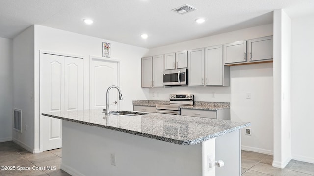 6878 Hartford Rd, Cocoa, FL 32927 - kitchen featuring appliances with stainless steel finishes, a sink, gray cabinetry, an island with sink, and light tile patterned floors