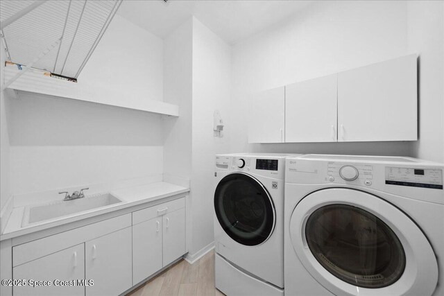 1019 Worthington Spring Dr, Melbourne, FL 32940 - clothes washing area featuring washer and clothes dryer, cabinet space, and light wood-style floors