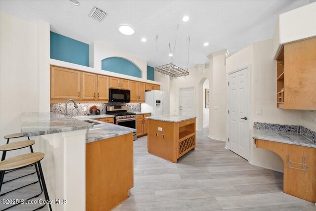 1019 Worthington Spring Dr, Melbourne, FL 32940 - kitchen featuring black microwave, gas stove, white fridge with ice dispenser, open shelves, and arched walkways