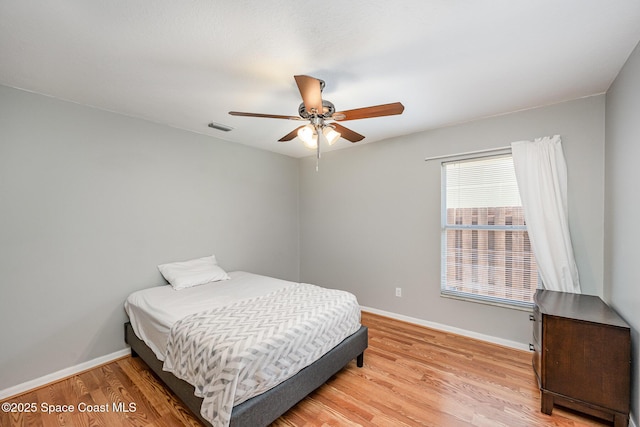 bedroom with baseboards, light wood-style flooring, ceiling fan, and visible vents