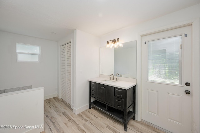 bathroom featuring vanity, a closet, wood finished floors, and a wealth of natural light