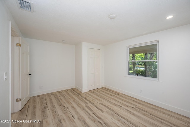 unfurnished bedroom with baseboards, a closet, light wood-type flooring, and visible vents