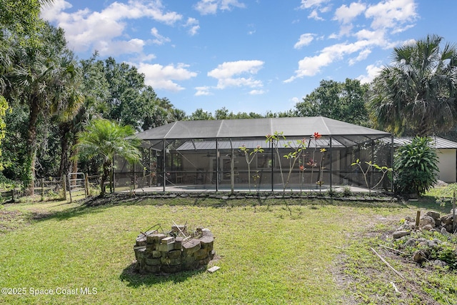 view of yard with a swimming pool, a fire pit, fence, and glass enclosure