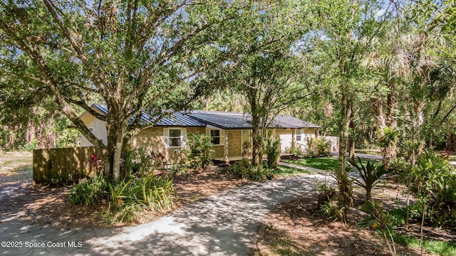 ranch-style home with aphalt driveway, fence, a standing seam roof, and metal roof