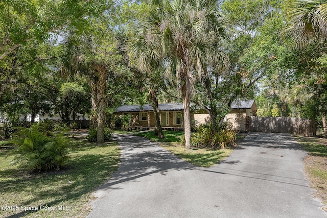 view of front of house featuring fence, metal roof, stone siding, and aphalt driveway