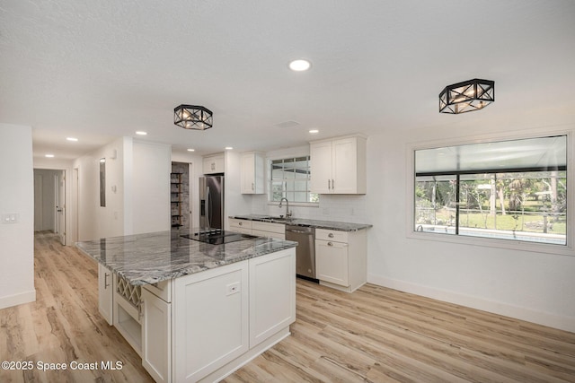 kitchen with a center island, a sink, baseboards, white cabinets, and stainless steel appliances