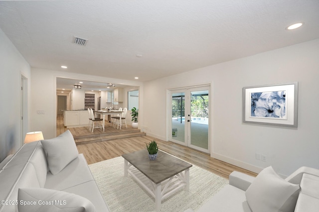 living room featuring recessed lighting, visible vents, french doors, and light wood finished floors