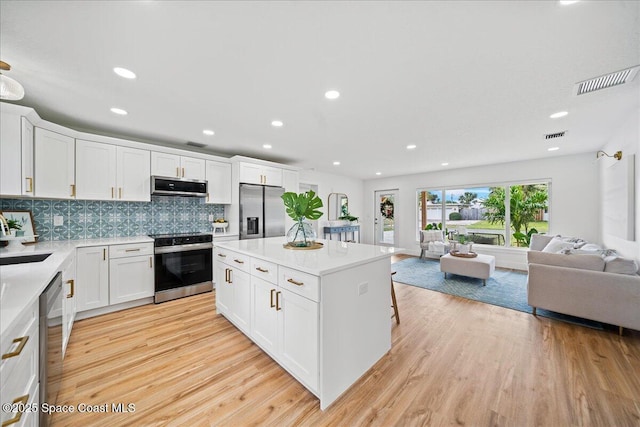 2059 Barracuda Ave, Melbourne Beach, FL 32951 - kitchen with visible vents, open floor plan, light wood-style floors, and stainless steel appliances