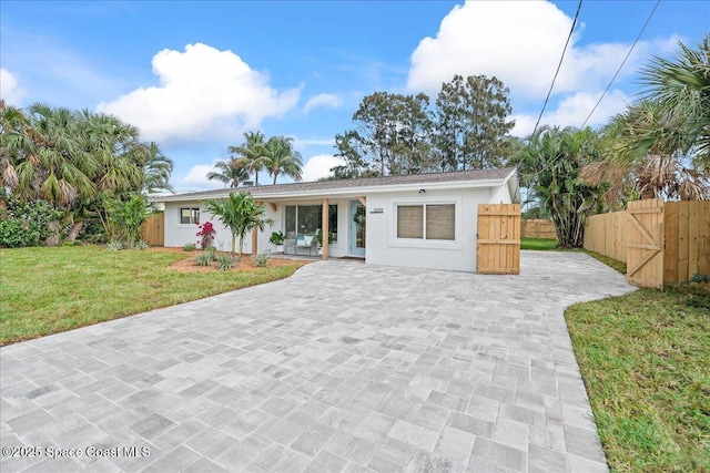 2059 Barracuda Ave, Melbourne Beach, FL 32951 - view of front of home featuring fence, a front yard, decorative driveway, stucco siding, and a gate