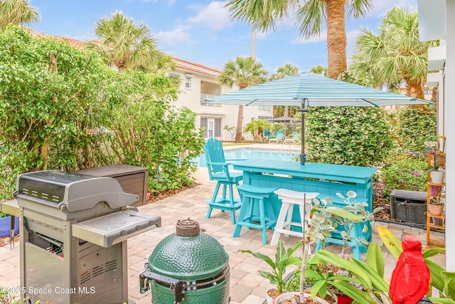view of patio / terrace with an outdoor pool, outdoor dry bar, and a grill