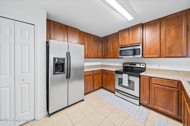 4016 Meander Pl Unit 207, Rockledge, FL 32955 - kitchen with stainless steel appliances, light countertops, light tile patterned flooring, and brown cabinetry