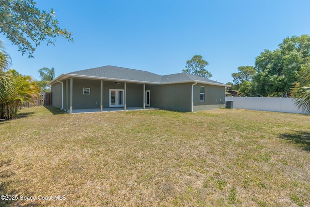 back of house featuring central AC, a patio, a fenced backyard, a ceiling fan, and a lawn