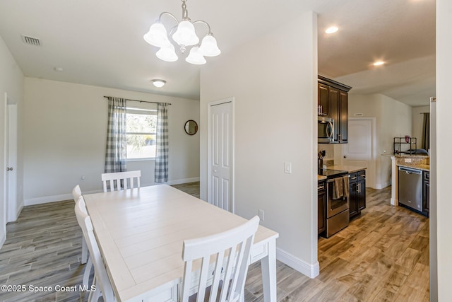 dining room with light wood-style floors, baseboards, visible vents, and a notable chandelier