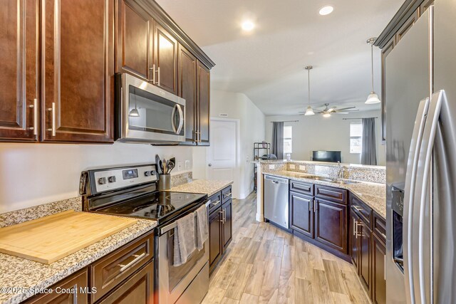 kitchen with ceiling fan, appliances with stainless steel finishes, a sink, open floor plan, and light wood-style flooring